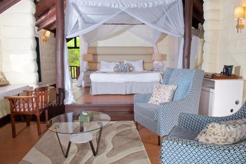 a bedroom with a bed and a table and chairs at The Great Rift Valley Lodge & Golf Resort in Naivasha