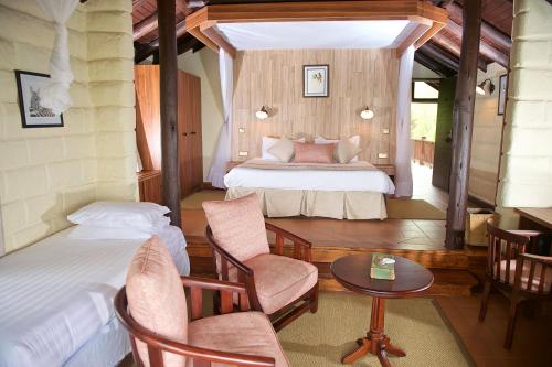 a bedroom with two beds and a table and chairs at The Great Rift Valley Lodge & Golf Resort in Naivasha