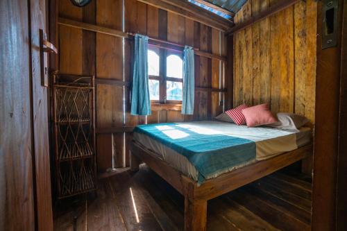 un letto in una stanza di legno con una finestra di Lost and Found a Koh Rong Sanloem