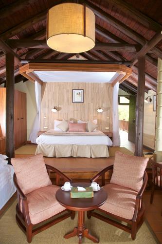 a bedroom with a bed and a table and chairs at The Great Rift Valley Lodge & Golf Resort in Naivasha