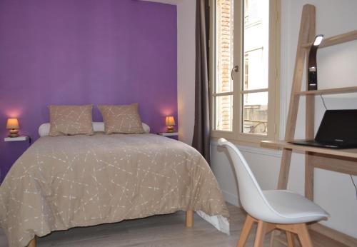 a purple bedroom with a bed and a white chair at Les Clochers d'Or in Chartres