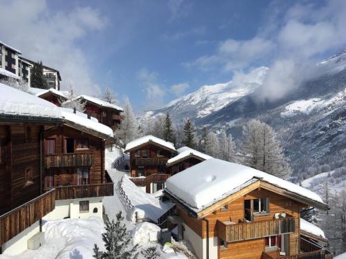 a log cabin in the snow with mountains in the background at Chalet Steinböckle****S in Saas-Fee