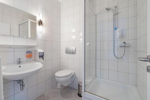 a bathroom with a toilet and a sink and a shower at Hotel Imota in Neuwied