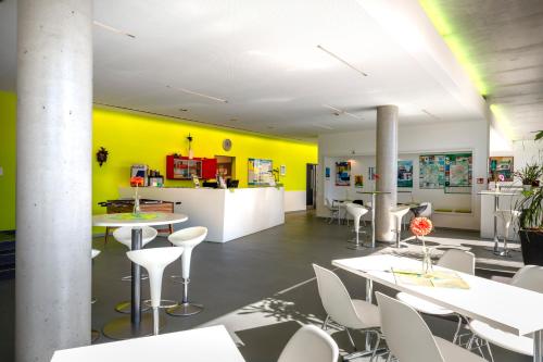 a room with white tables and chairs and a yellow wall at Jugendherberge Schweinfurt in Schweinfurt