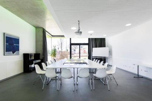 a dining room with a white table and chairs at Jugendherberge Schweinfurt in Schweinfurt