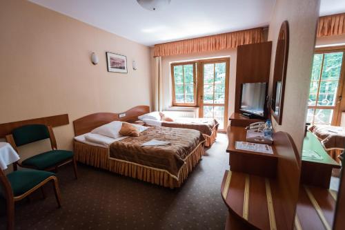 a hotel room with two beds and a television at Gościniec pod Bukiem in Głuchołazy