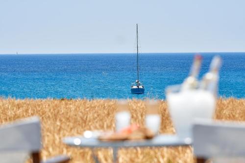a sailboat in the ocean with a table and a boat at Muses Rooms Milos in Provatas