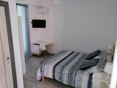 a bedroom with a bed and a desk and a television at UP&B Rooms Catania in Mascalucia