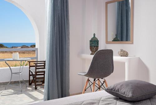 a bedroom with a bed and a chair and a table at Muses Rooms Milos in Provatas