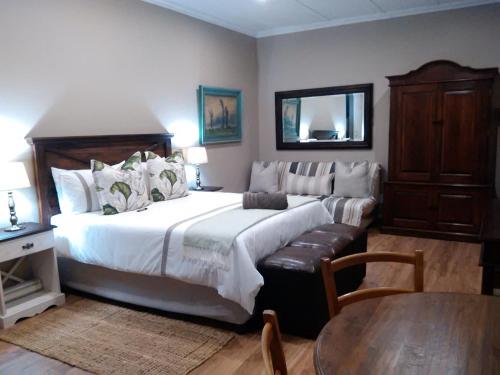 Un dormitorio con una gran cama blanca y una mesa en Welcome Home Cottages en Pietermaritzburg