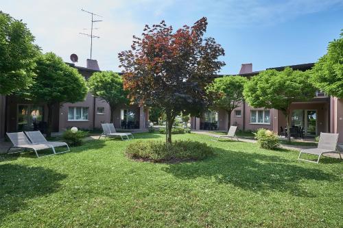 a yard with white chairs and a tree at Villaggio Turistico Lugana Marina in Sirmione