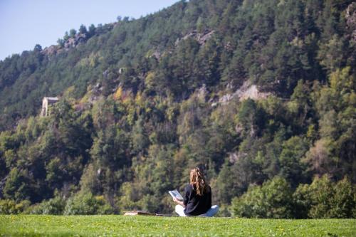 a woman sitting on a hill reading a book at Hotel Rural-Spa Resguard Dels Vents in Ribes de Freser