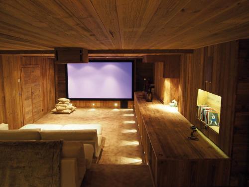 a living room with a large screen in a building at Chalet Javen - 520m2 avec piscine chauffée et home cinéma in Megève