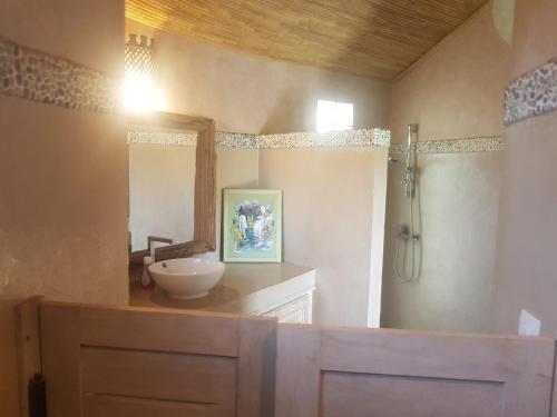 a bathroom with a sink and a shower with a mirror at Keur Palmier Saly in Saly Portudal