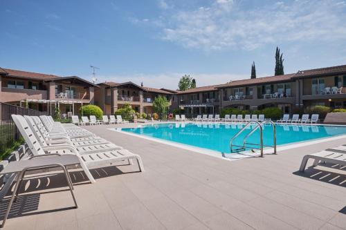 a swimming pool with lounge chairs next to a resort at Villaggio Turistico Lugana Marina in Sirmione