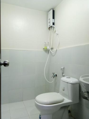 a white bathroom with a toilet and a sink at Your Holiday Home( Studio, King Size Bed) in Mactan
