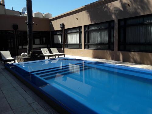 康科迪亞的住宿－Cristobal Hotel Boutique，一座蓝色游泳池,旁边是一座建筑,配有两把椅子