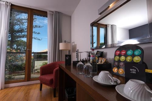 a room with a bar with a red chair and a window at ARTS IN Hotel Conde Carvalhal in Funchal