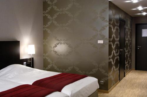 a bedroom with a bed and a wall with wallpaper at Biznis Hotel in Lokeren