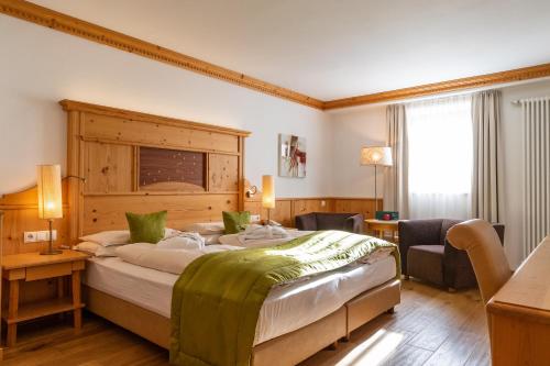 Schlafzimmer mit einem großen Bett mit einem Kopfteil aus Holz in der Unterkunft Vitalpina Hotel Dosses in St. Christina in Gröden
