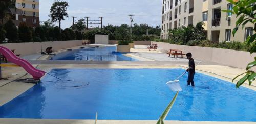 un hombre con un cubo en una piscina en Your Holiday Home( Studio, King Size Bed), en Mactan