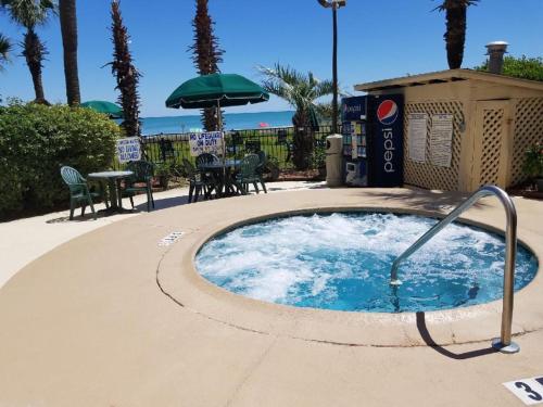 a hot tub in a patio with a table and umbrella at The Palms Resort-Oceanfront in Myrtle Beach