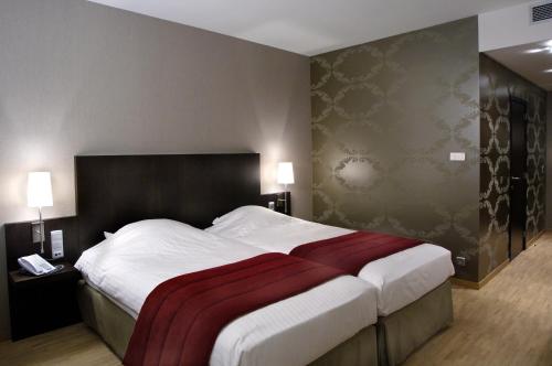 a bedroom with a large bed with a red blanket on it at Biznis Hotel in Lokeren