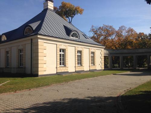a white building with a black roof on a field at Pałac w Krzelowie in Krzelów