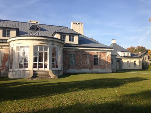 a large brick house with a conservatory on a lawn at Pałac w Krzelowie in Krzelów