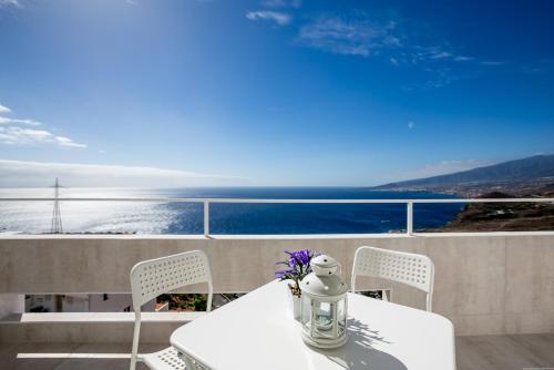 uma mesa e cadeiras brancas com vista para o oceano em Breathtaking 180 degrees Views in Tabaiba Alta em Santa Cruz de Tenerife