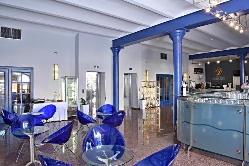 a room with blue chairs and a bar at LH Hotel Dvořák Tábor Congress & Wellness in Tábor