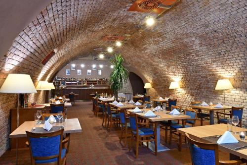 a restaurant with wooden tables and chairs and a brick wall at LH Hotel Dvořák Tábor Congress & Wellness in Tábor