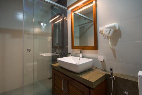 a bathroom with a sink and a mirror and a shower at Ceyloni City Hotel in Kandy