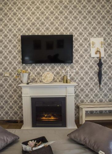 a living room with a fireplace with a television on a wall at Barberini Dream in Rome