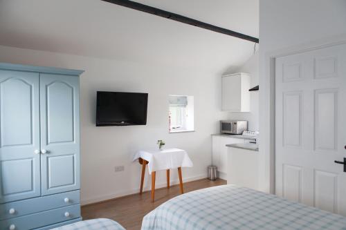 a bedroom with a bed and a table and a tv at Elm Cottage Touring Park in Whitegate