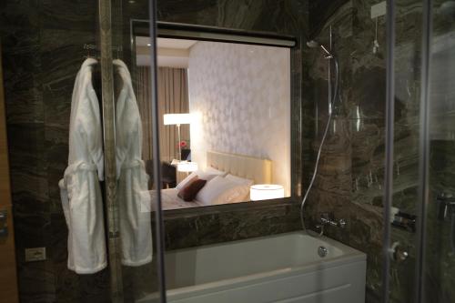 a bathroom with a mirror of a bed and a tub at Best Western Premier Ark Hotel in Tirana