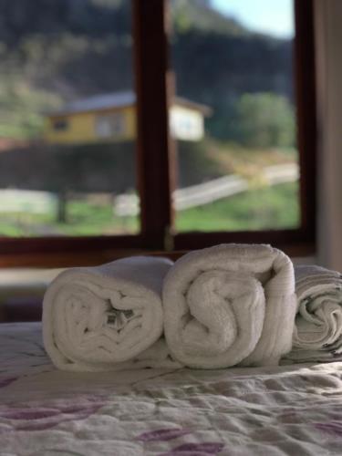 a pile of towels on a bed with a window at Casa Cambuí Hospedagem Rural in São José do Rio Preto