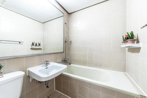 a bathroom with a sink and a tub and a mirror at HK Resort in Sokcho