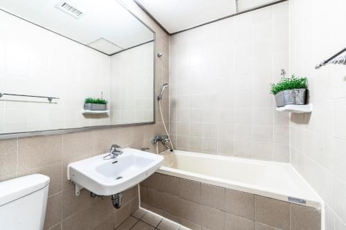 a bathroom with a sink and a bath tub and a mirror at HK Resort in Sokcho