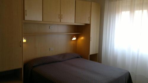 a small bedroom with a bed and a window at Hotel Erika in Caorle