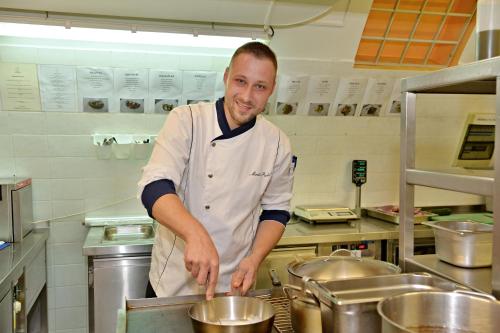 a man standing in a kitchen preparing food at LH Hotel Dvořák Tábor Congress & Wellness in Tábor