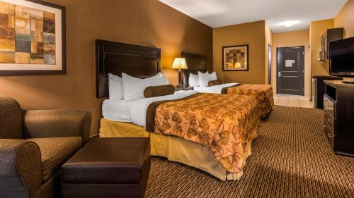 Best Western Plus Estevan Inn & Suites في Estevan: غرفة فندقية بسريرين واريكة