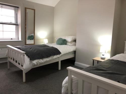 a bedroom with two beds and a mirror at No 5 New Inn Apartments in Newark-on-Trent