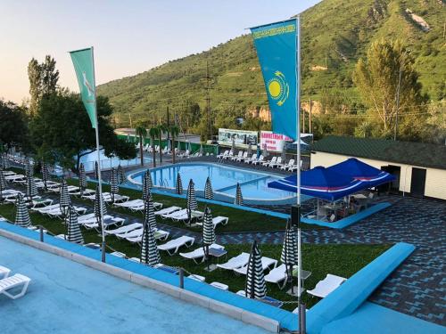 a pool at a resort with lounge chairs and a mountain at Sunkar Hotel in Almaty