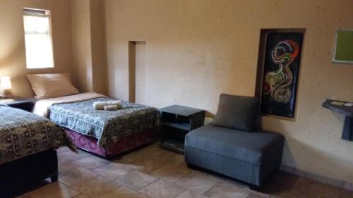 a hotel room with two beds and a chair at Arek's Place in Krugersdorp