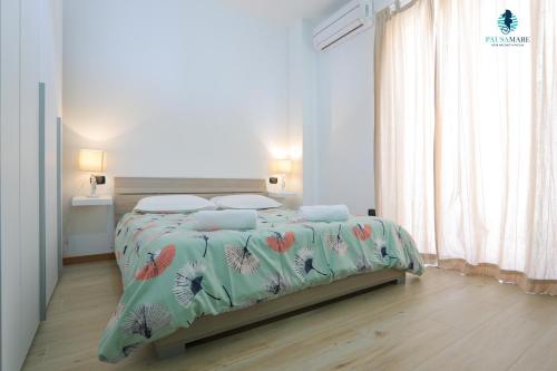 - une chambre blanche dotée d'un lit avec un couvre-lit floral dans l'établissement Pausa Mare Apartment, à Polignano a Mare