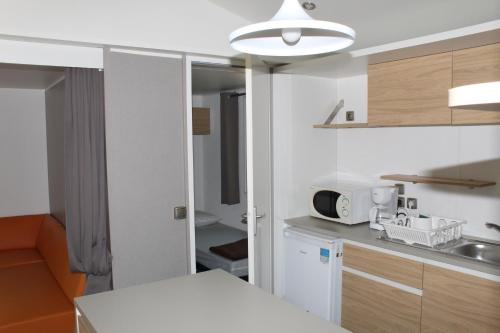 a kitchen with a microwave and a counter top at Camping de la Chapelette in Saint-Martin-de-Crau