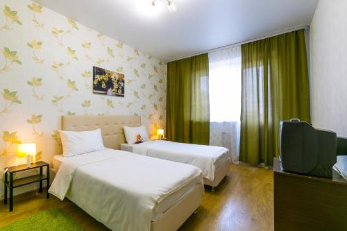 ポドリスクにあるDobrye Sutki - Komandirovka 6+のベッド2台、薄型テレビが備わるホテルルームです。