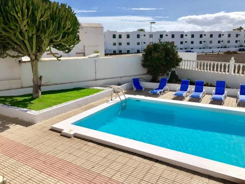 a swimming pool with blue chairs next to a building at Casa Margarita in Puerto del Carmen