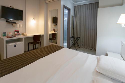a hotel room with a large white bed and a desk at Valerim Florianópolis in Florianópolis